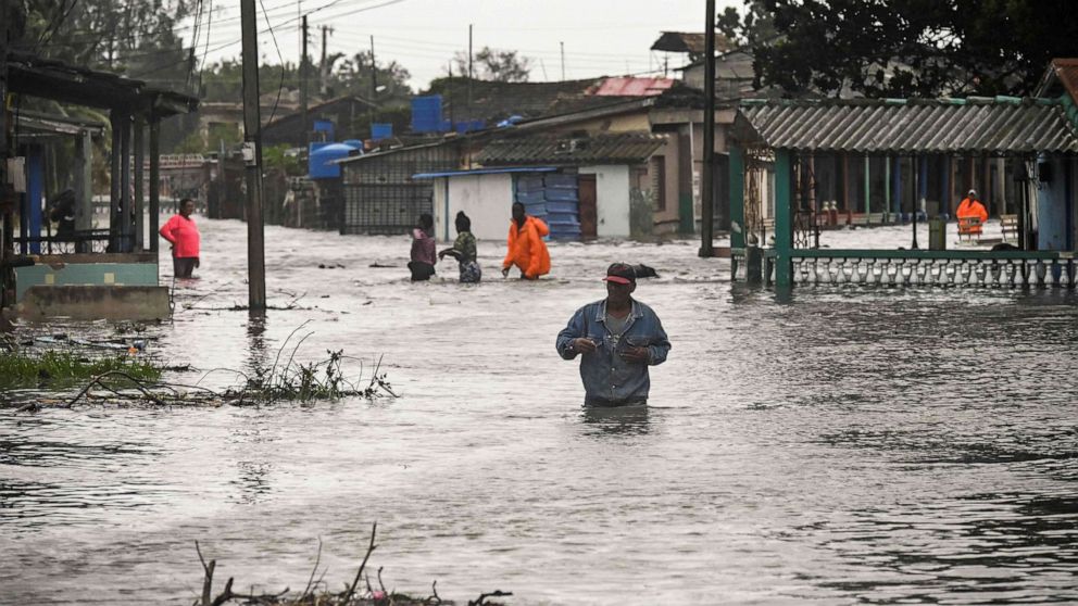 PHOTO: People walk through a flooded street in Batabano, Cuba, Sept. 27, 2022, during the passage of Hurricane Ian.