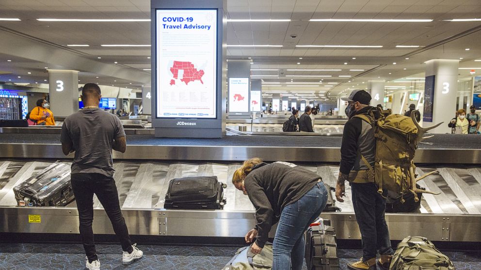 PHOTO: A Covid-19 advisory is displayed on a screen as travelers collect luggage in the baggage claim area of Terminal B at LaGuardia Airport in New York, Sept. 28, 2020.