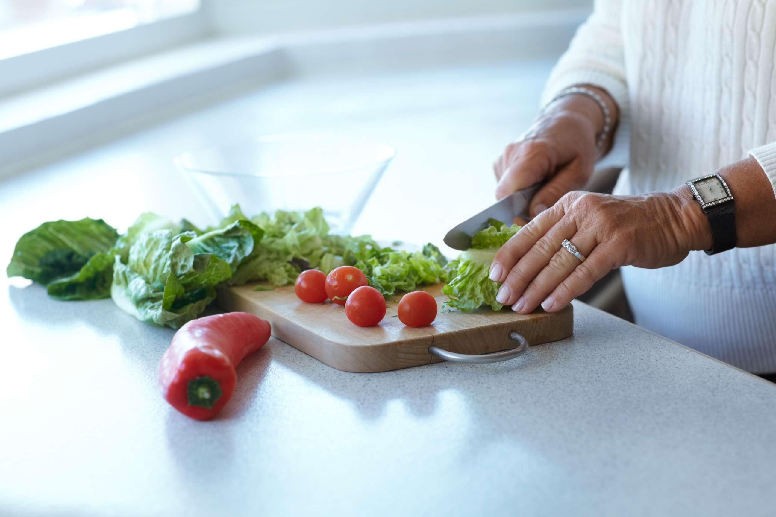 PHOTO: In this undated stock photo, a woman cuts up romaine lettuce on a cutting board for a salad.