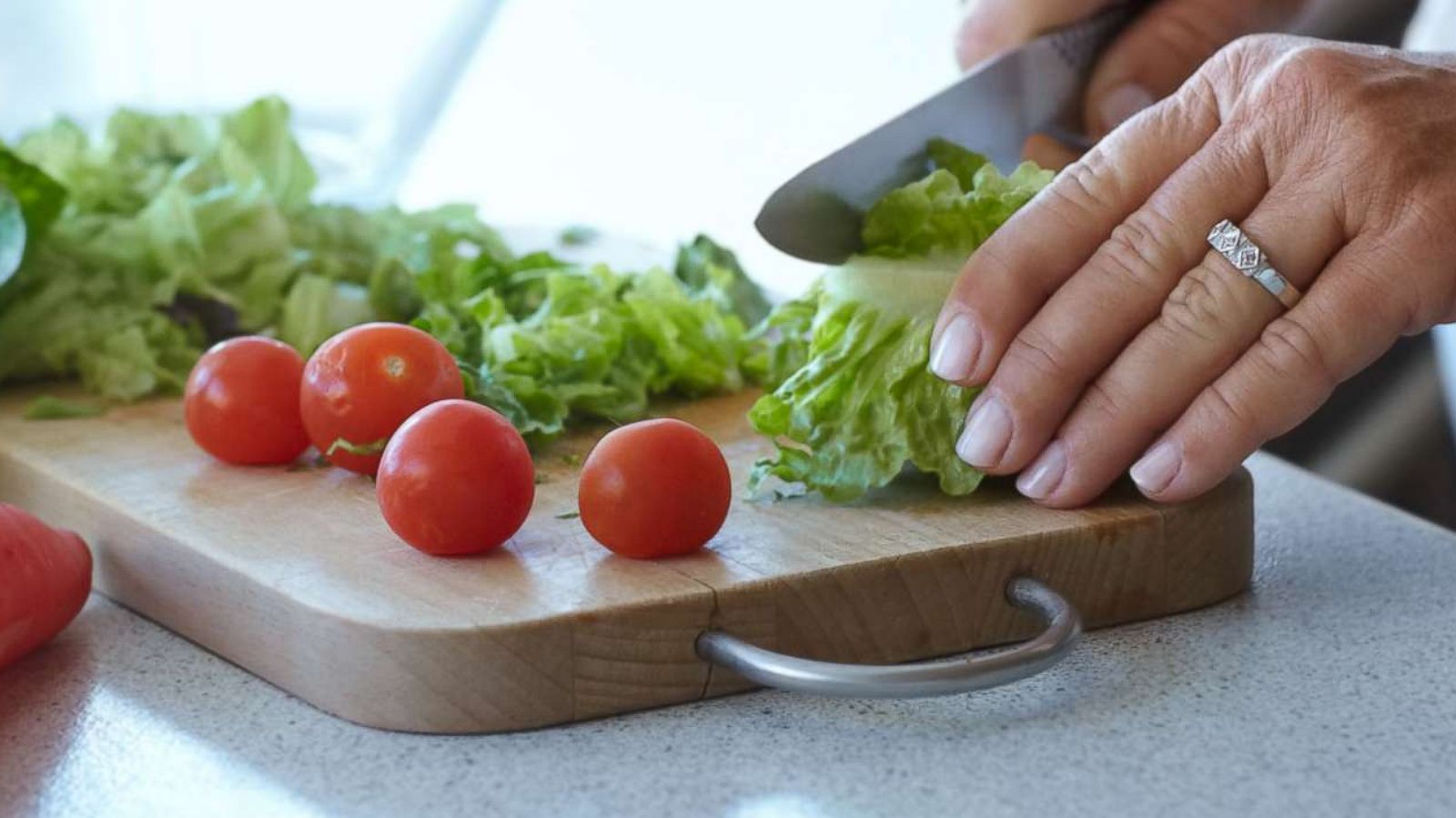 PHOTO: In this undated stock photo, a woman cuts up romaine lettuce on a cutting board for a salad.