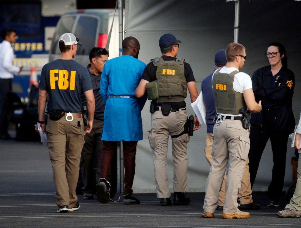 PHOTO: Federal agents hold a detainee after predawn raids that saw dozens of people arrested, Aug. 22, 2019, in Los Angeles. 80 people were charged with participating in a conspiracy to steal millions through a range of fraud schemes and money laundering.