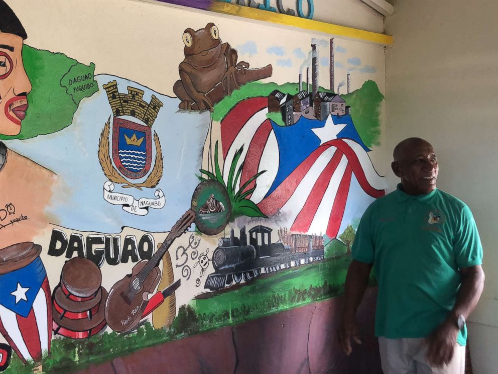 Community leader Angel Colon poses next a mural dedicated to the town of Daguao.