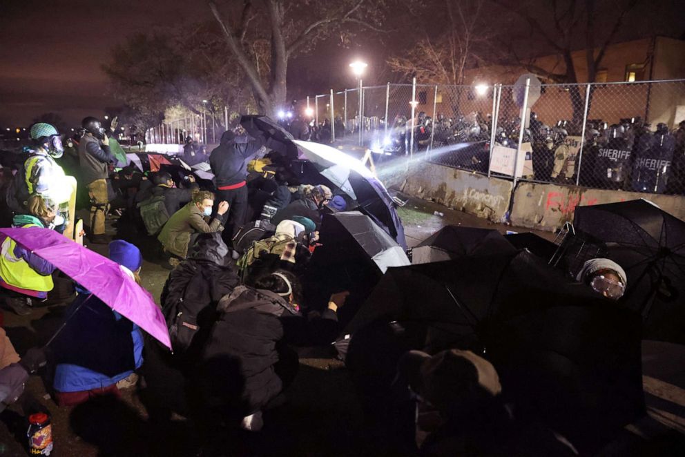 PHOTO: Demonstrators use umbrellas for protection as police fire pepper spray and rubber bullets during a protest outside of the Brooklyn Center police station on April 14, 2021, in Brooklyn Center, Minn.