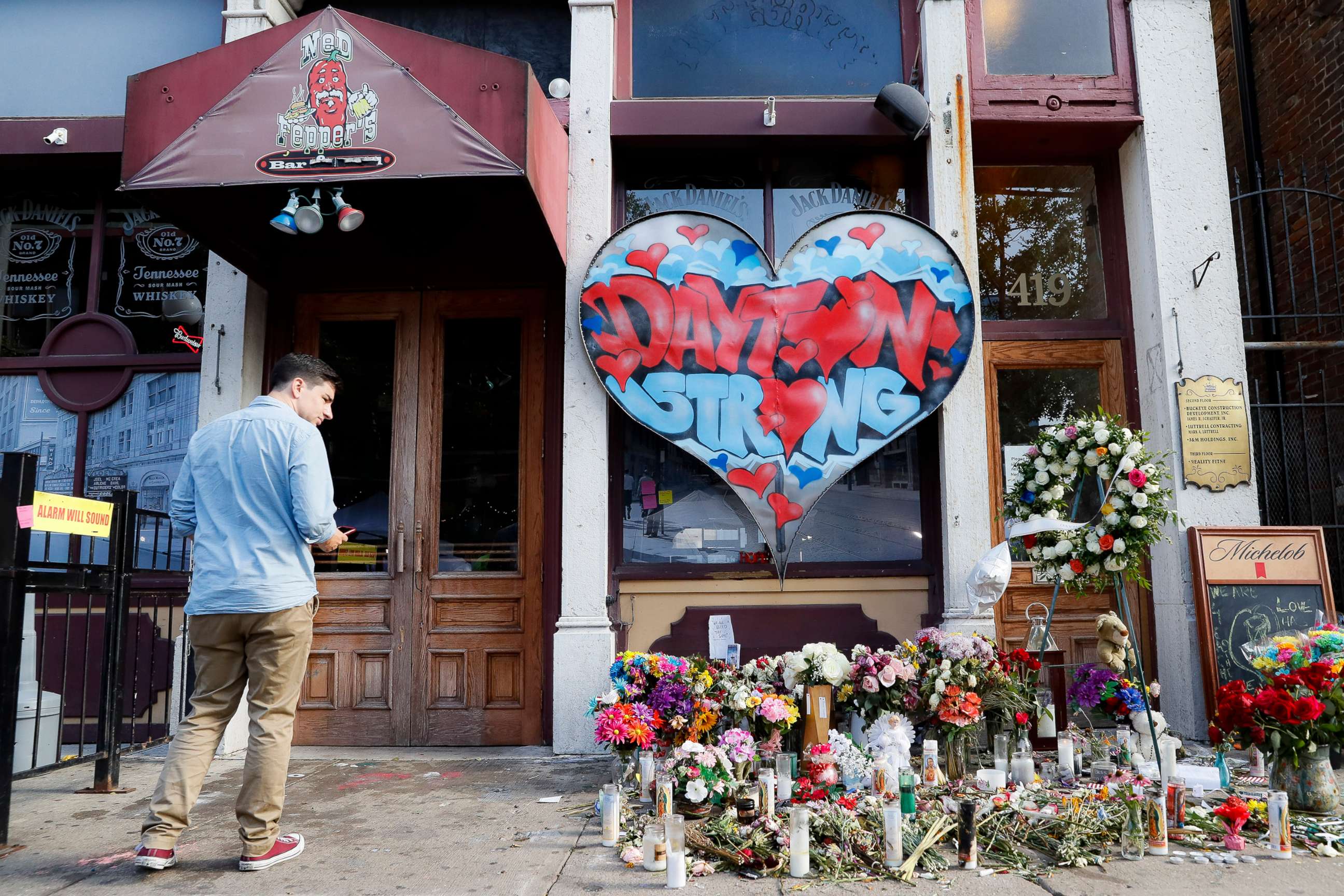 PHOTO: A pedestrian passes a makeshift memorial for the slain and injured victims of a mass shooting that occurred in the Oregon District early Sunday morning, Wednesday, Aug. 7, 2019, in Dayton, Ohio.