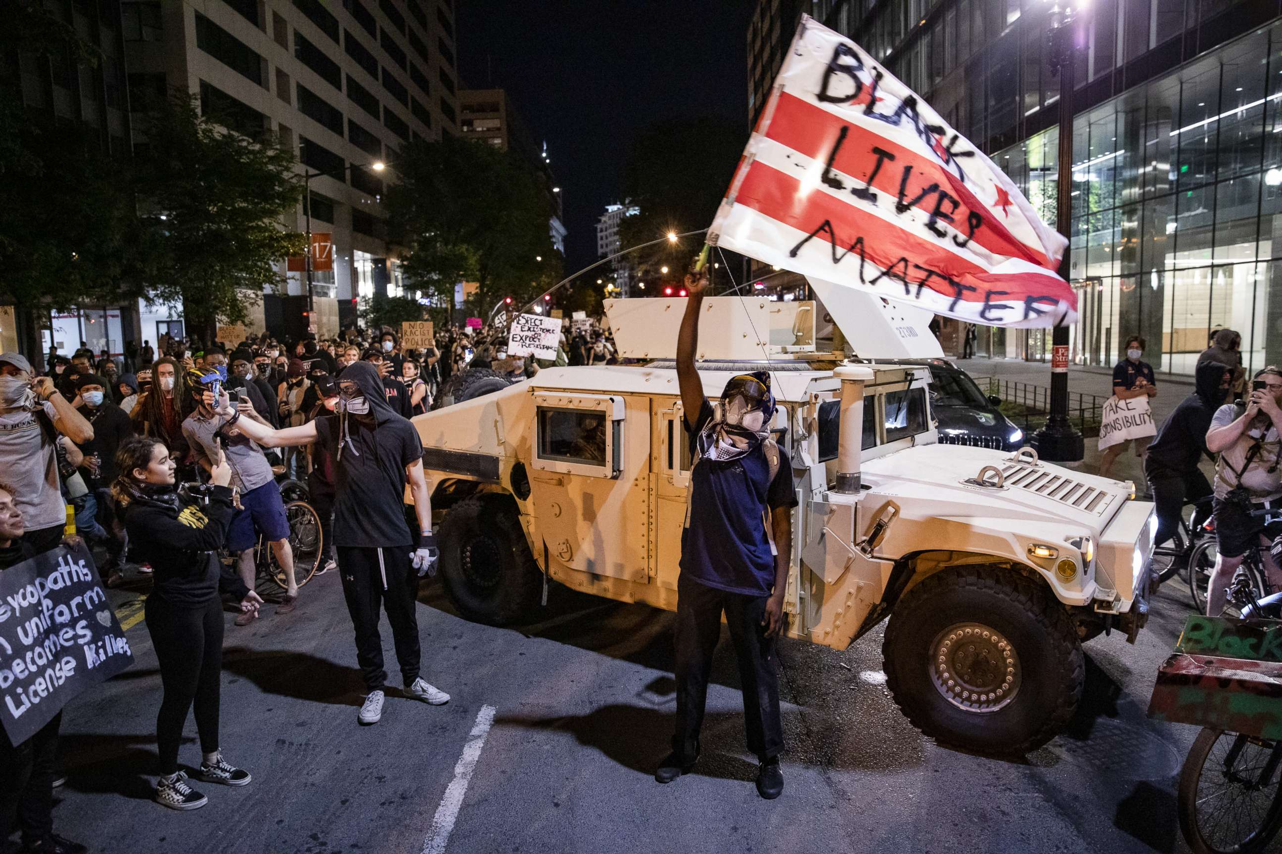 PHOTO: A protester waves a D.C. flag with Black Lives Matter spray painted on it next to a DC National Guard Humvee as people march through the streets during a demonstration over the death of George Floyd, June 2, 2020, in Washington, D.C.