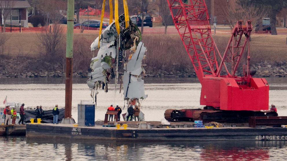 PHOTO: A large portion of the damaged plane fuselage is lifted from the Potomac River during recovery efforts after the American Airlines crash on Feb. 03, 2025 in Arlington, Va.
