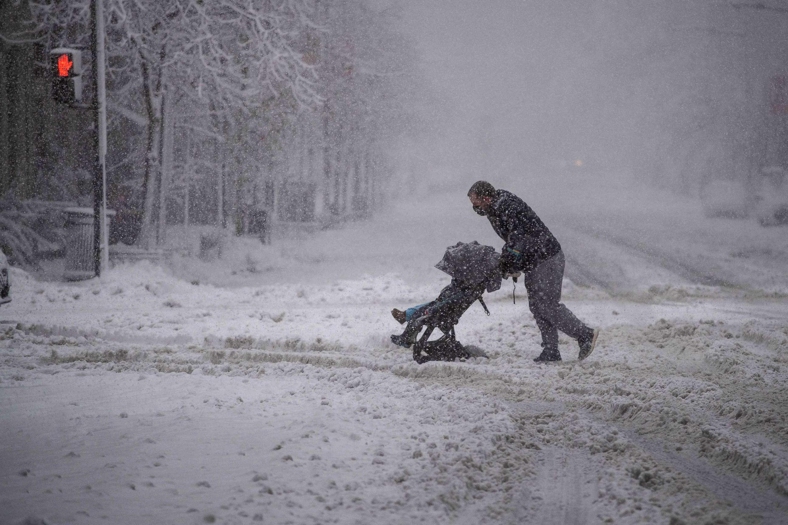 PHOTO: A man tries to negotiate crossing a street with a double baby stroller during a snow storm in downtown Washington, D.C., Jan. 3, 2022, as a winter storm brought heavy snow to the region.