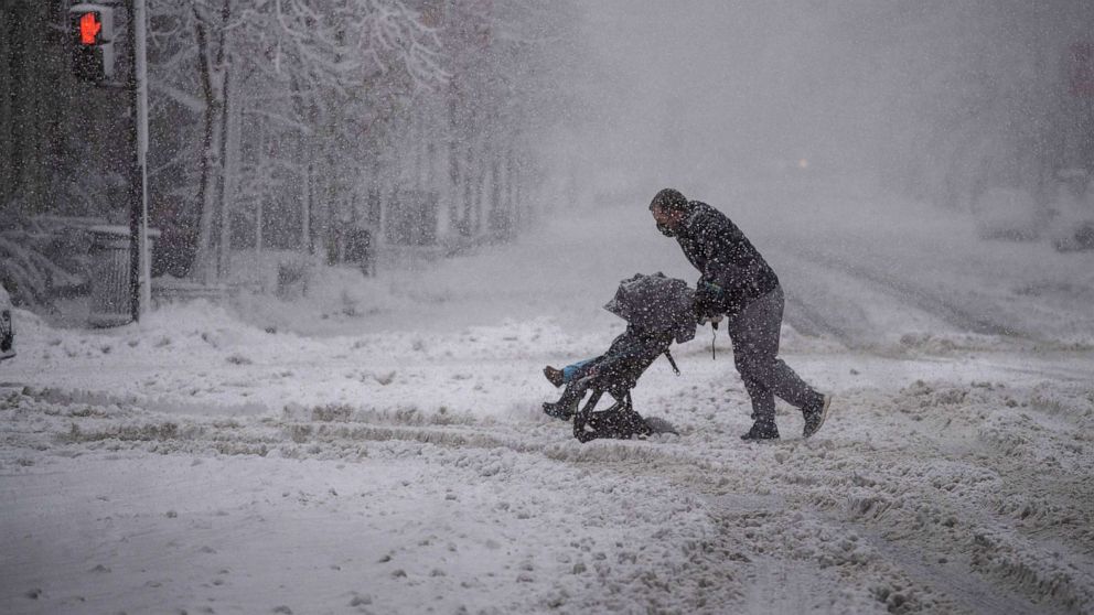 PHOTO: A man tries to negotiate crossing a street with a double baby stroller during a snow storm in downtown Washington, D.C., Jan. 3, 2022, as a winter storm brought heavy snow to the region.