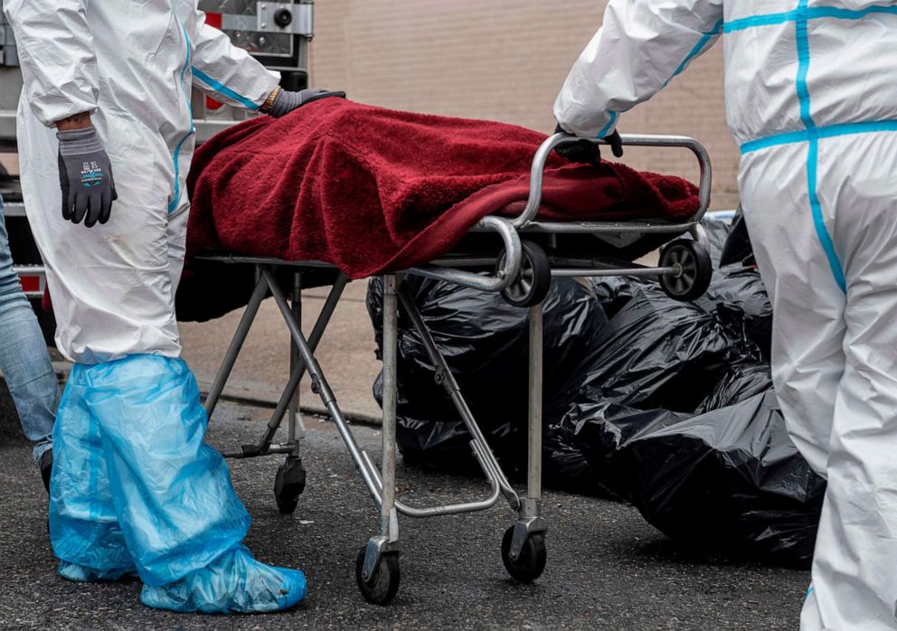 PHOTO: In this file photo taken on April 30, 2020, people in hazmat suits transport a deceased person on a stretcher outside a funeral home in the New York City borough of Brooklyn on April 30, 2020.