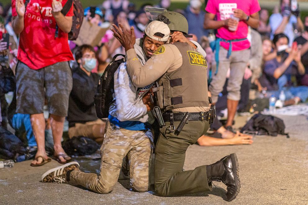 PHOTO: A protester and a Los Angeles County Sheriff's Department deputy embrace in solidarity as officers prepare to arrest a large group of people demonstrating past curfew over the death of George Floyd in Los Angeles,  June 3, 2020.