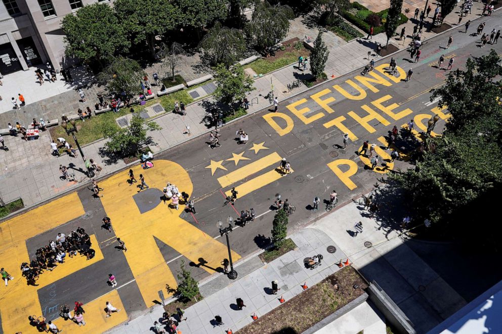 PHOTO: A sign painted by protesters reading "Defund the Police" is painted next to a "Black Lives Matter" sign painted on 16th Street near the White House in Washington, D.C., June 7, 2020.