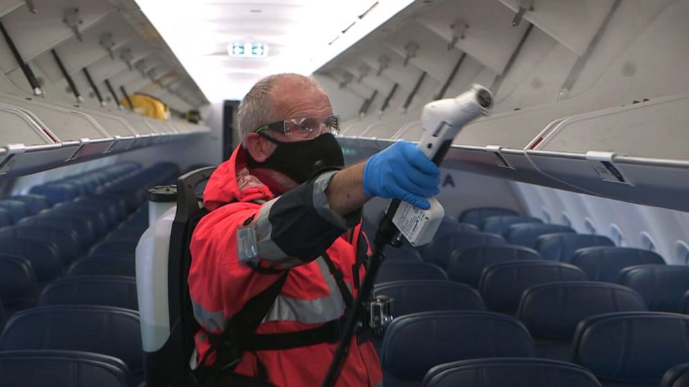 PHOTO: A man cleans a Delta plane with an electrostatic sprayer.