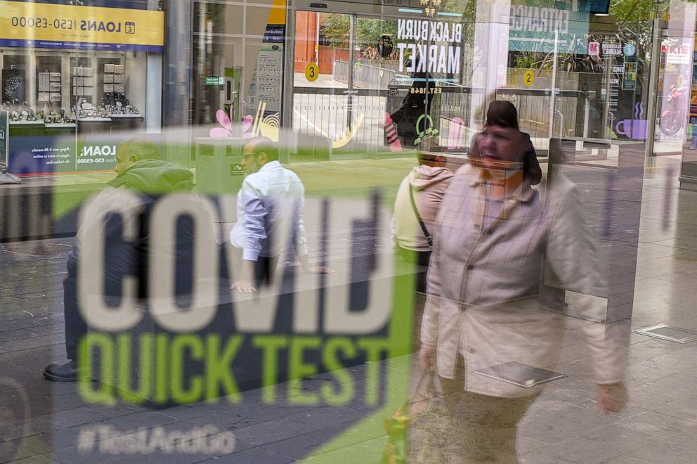 PHOTO: A pedestrian wearing a passes a Covid-19 information sign in the window of the Bus Station in Blackburn, north west England on June 16, 2021. The UK government on Monday announced a four-week delay to the full lifting of c