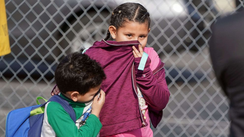 PHOTO: Children cover their noses and mouths while leaving school where 26 people were treated for jet fuel exposure at Park Avenue Elementary School in Cudahy, Calif., Jan. 14, 2020.