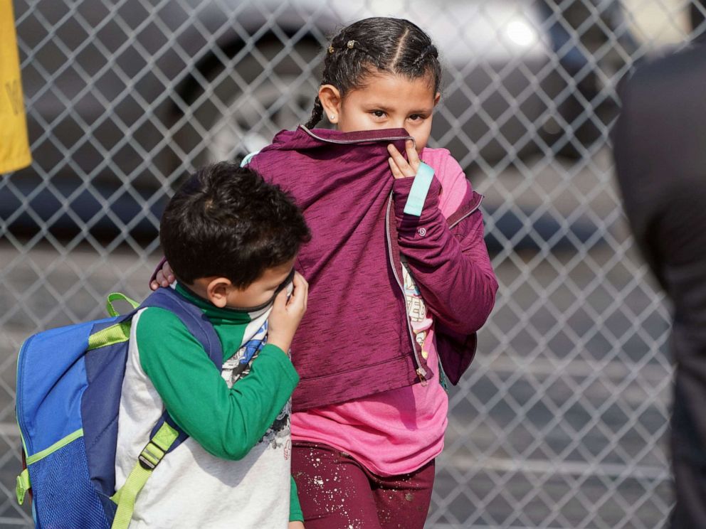 PHOTO: Children cover their noses and mouths while leaving school where 26 people were treated for jet fuel exposure at Park Avenue Elementary School in Cudahy, Calif., Jan. 14, 2020.