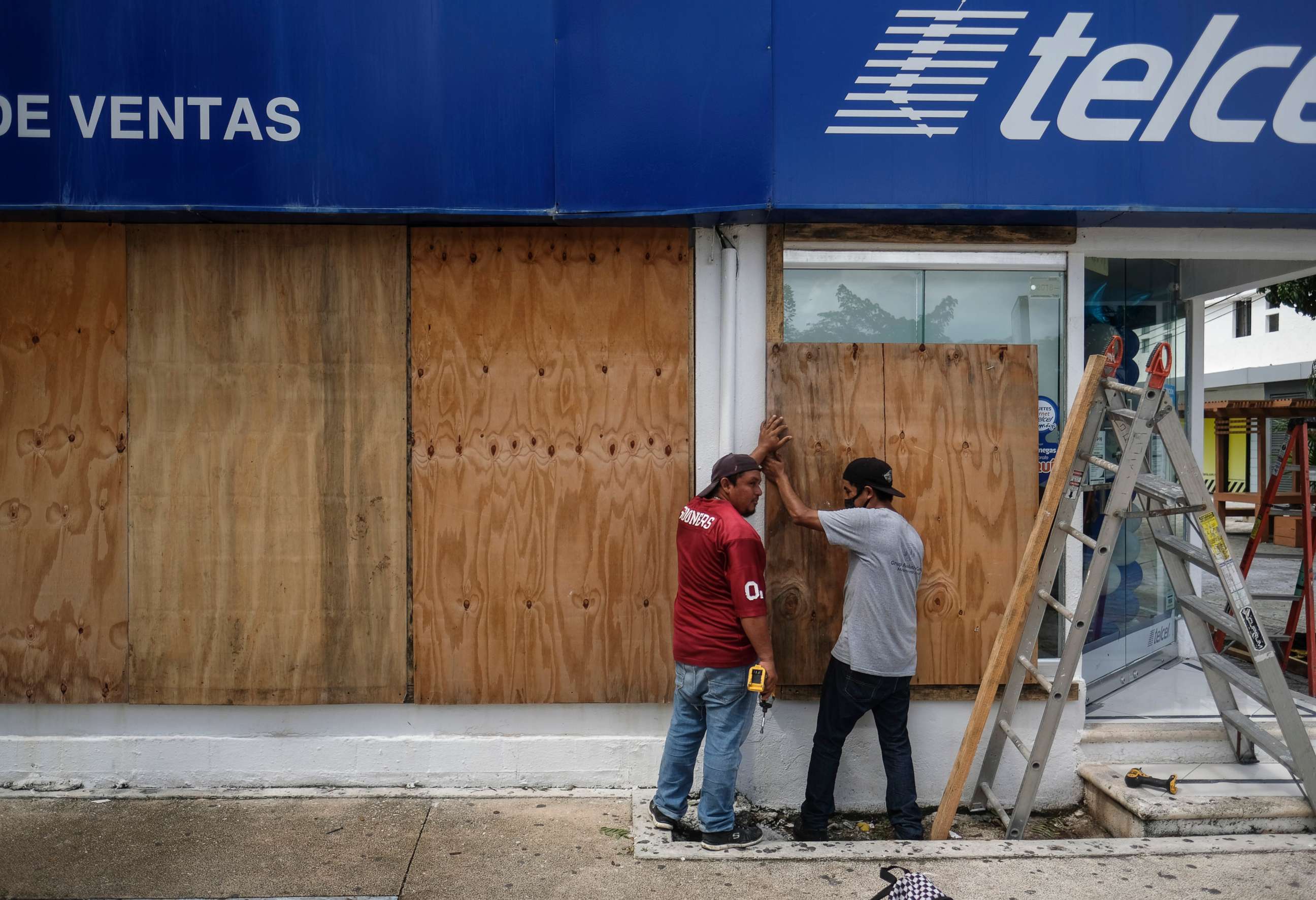 PHOTO: Men board up a Telcel phone store as Hurricane Delta approaches Puerto Juarez, Cancun, Mexico, Oct. 6, 2020.