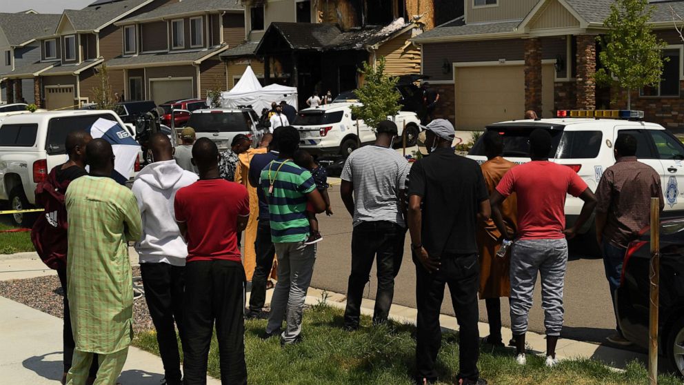 PHOTO: Members of the Senegalese community watch as bodies are removed from a burnt home after five people were killed inside on Aug. 5, 2020, in Denver.