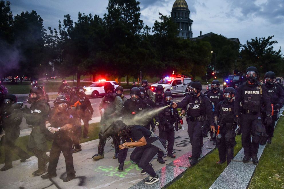 PHOTO: ]Police officers pepper spray a woman next to the Colorado State Capitol as protests against the death of George Floyd continue for a third night on May 30, 2020, in Denver. 