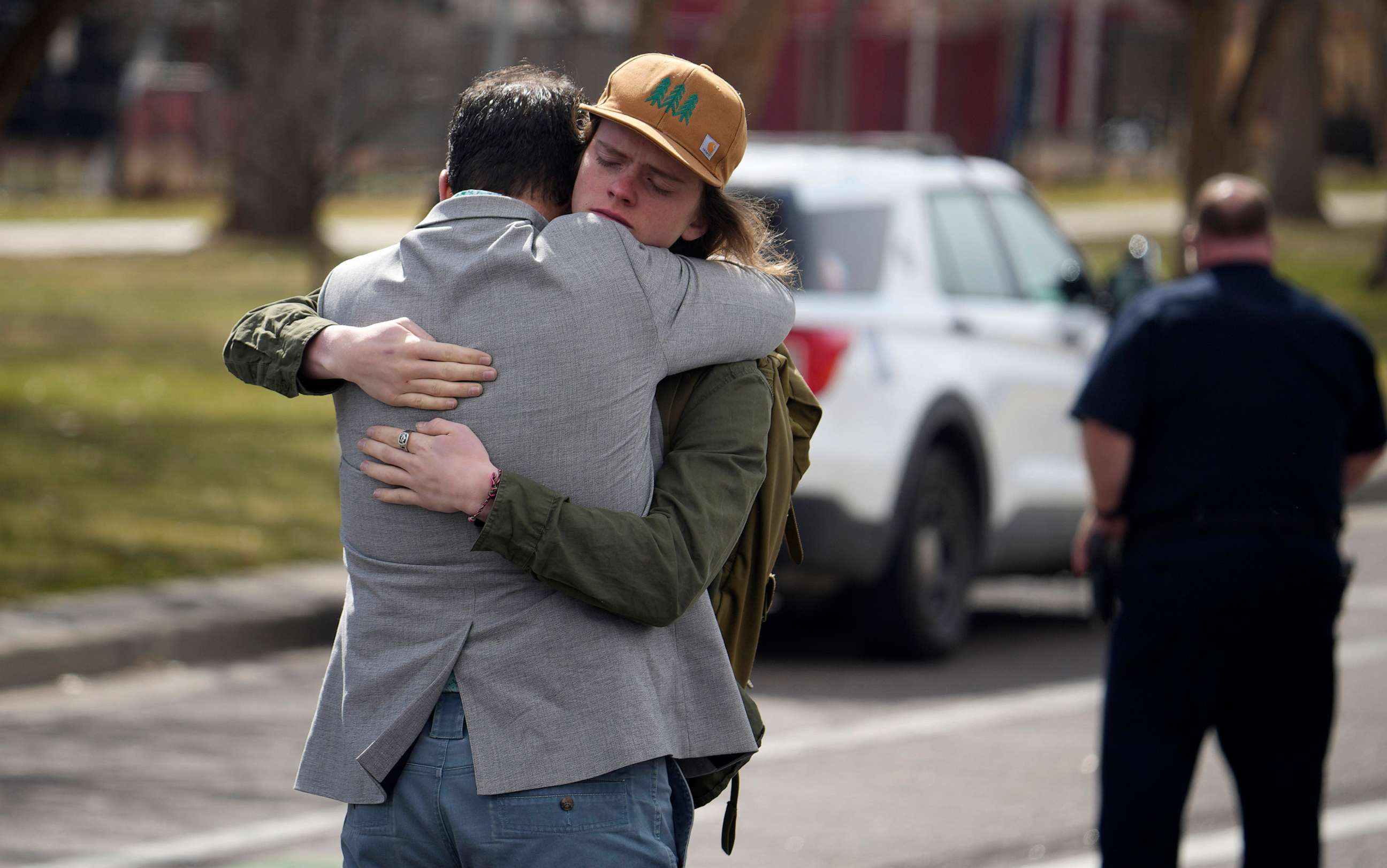 PHOTO: A student, right, hugs a man after a school shooting at East High School, March 22, 2023, in Denver.