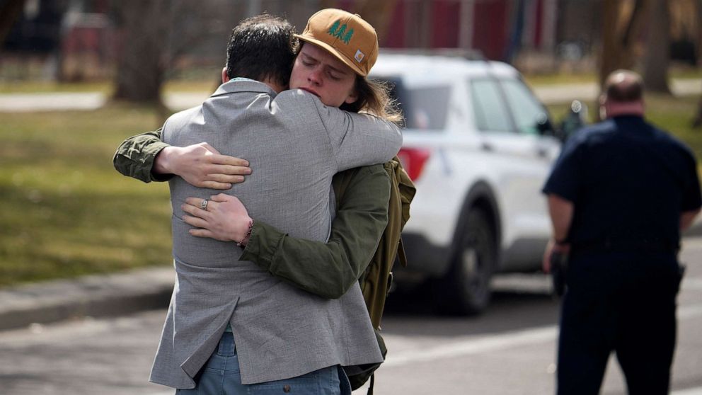 PHOTO: A student, right, hugs a man after a school shooting at East High School, March 22, 2023, in Denver.