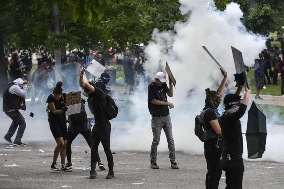 PHOTO: People react as police officers discharge tear gas next to the Colorado State Capitol as protests against the death of George Floyd continue for a third night on May 30, 2020, in Denver. 