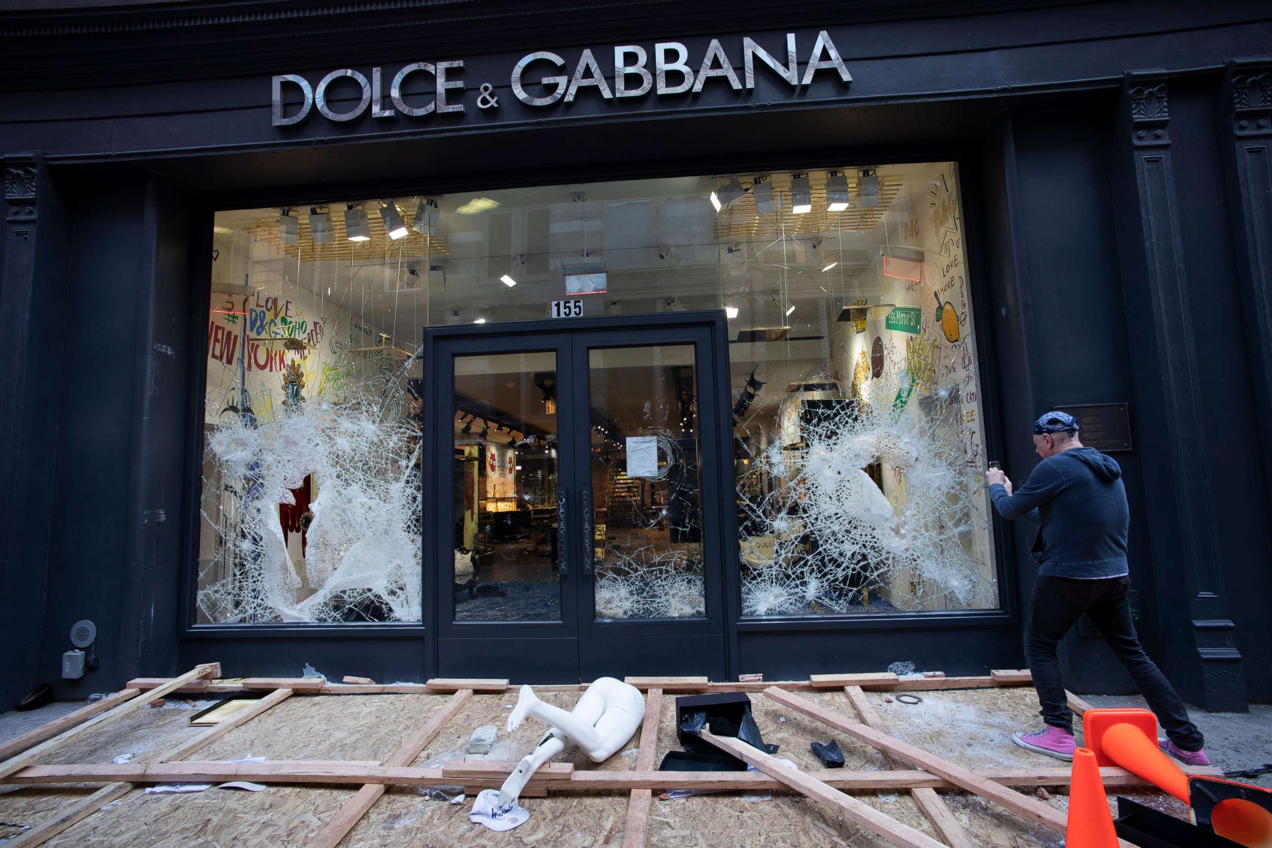 PHOTO: A passerby photographs a smashed Dolce and Gabbana store window in the SoHo neighborhood of New York City, June 1, 2020. 