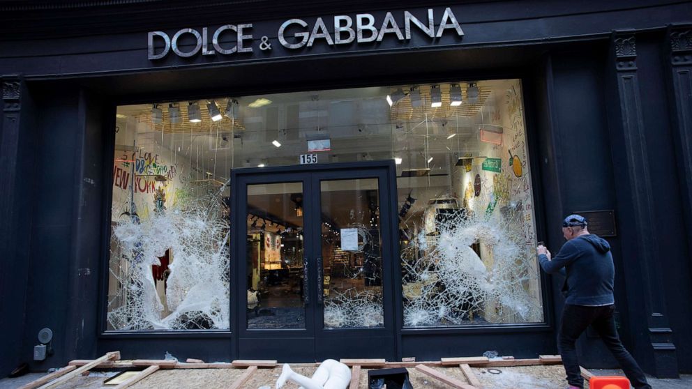 PHOTO: A passerby photographs a smashed Dolce and Gabbana store window in the SoHo neighborhood of New York City, June 1, 2020. 