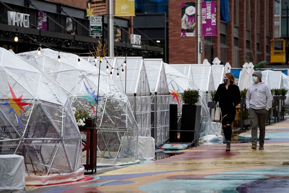 PHOTO: People walk by outdoor plastic dining bubbles on Fulton Market in Chicago, Oct. 18, 2020.