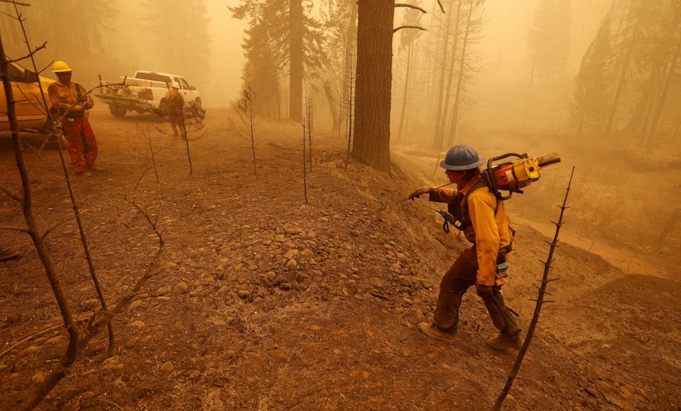 PHOTO: A firefighter with a chainsaw hikes back to the road in heavy smoke at the site of the Dixie Fire, a wildfire near the town of Greenville, Calif., Aug. 7, 2021. 