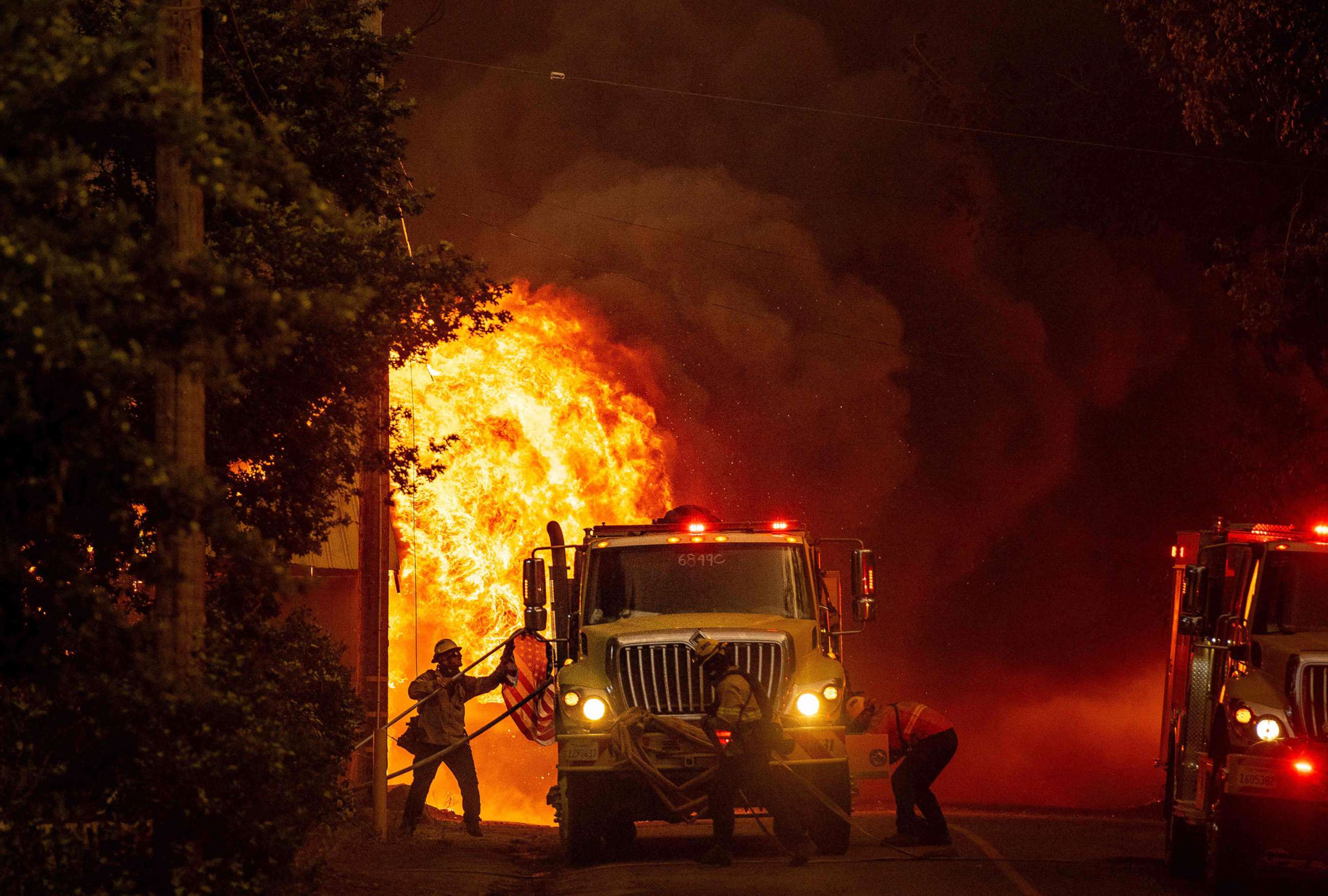 PHOTO: A firefighter saves an American flag as flames consume a home during the Dixie fire in Greenville, Calif., Aug. 4, 2021.