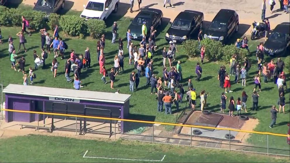 PHOTO: People gather a short distance from Dixon High School in Dixon, Ill., after a police officer confronted and injured an armed man at the school, May 16, 2018.