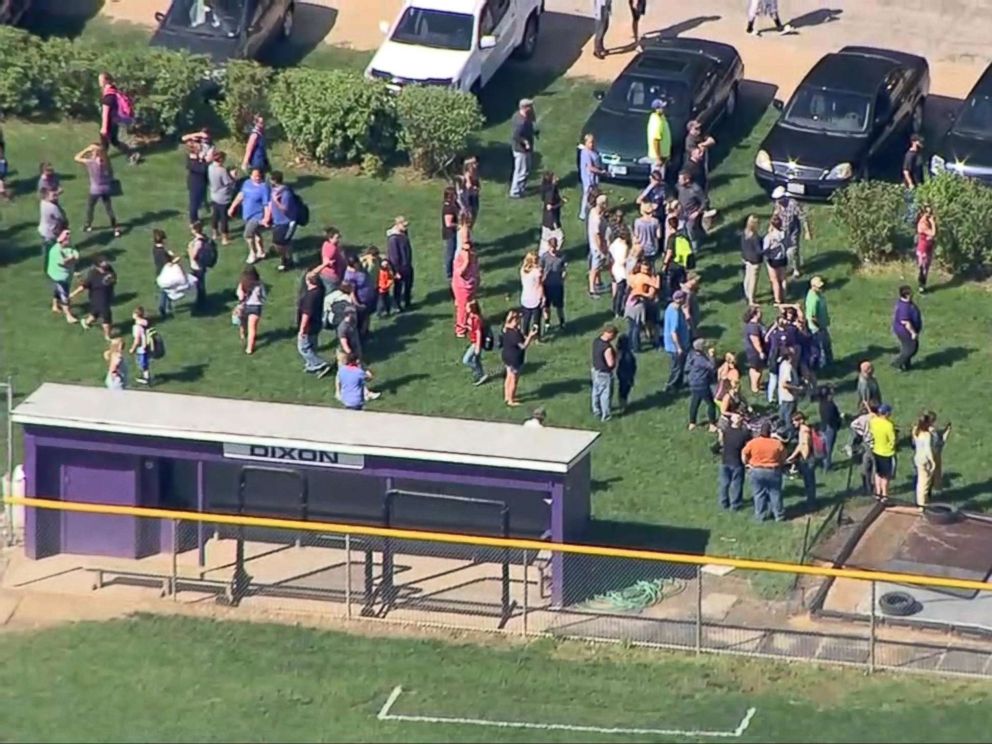 PHOTO: People gather a short distance from Dixon High School in Dixon, Ill., after a police officer confronted and injured an armed man at the school, May 16, 2018.