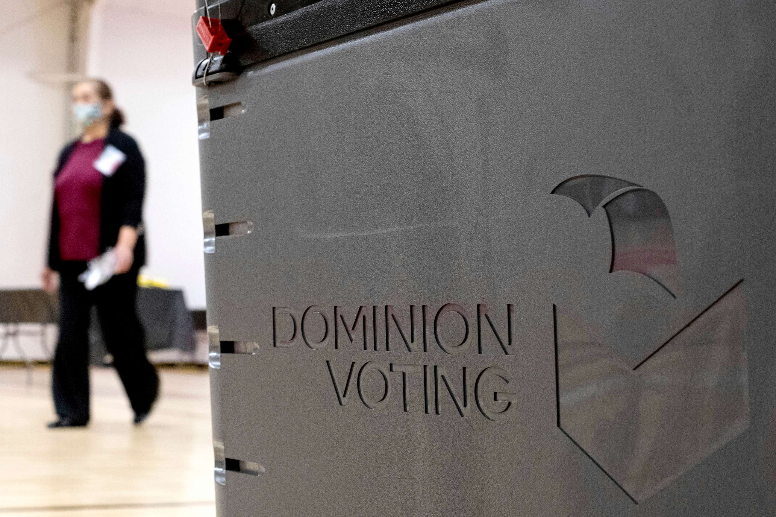 PHOTO: A worker passes a Dominion Voting ballot scanner while setting up a polling location at an elementary school in Gwinnett County, Ga., Jan. 4, 2021.