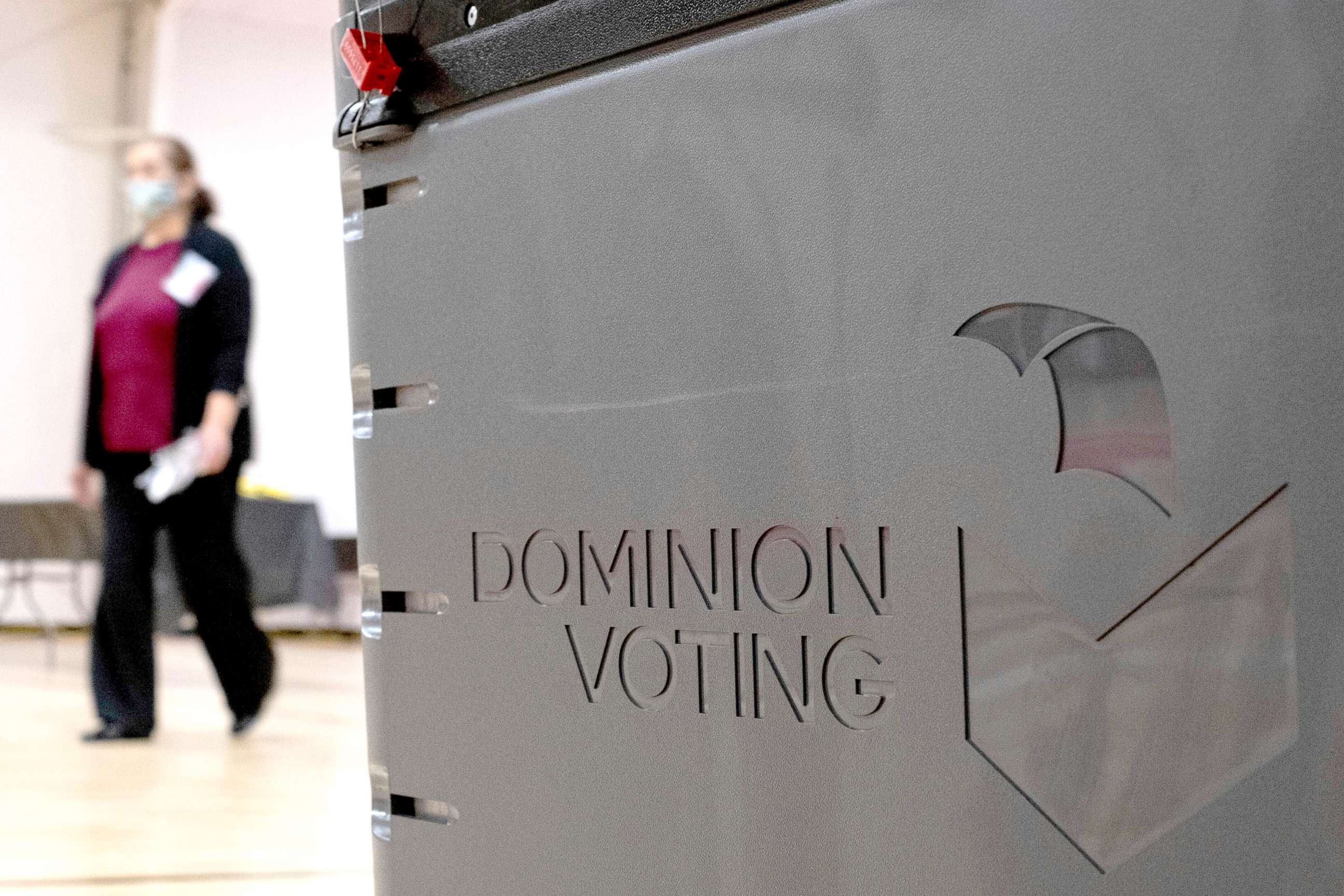 PHOTO: A worker passes a Dominion Voting ballot scanner while setting up a polling location at an elementary school in Gwinnett County, Ga., outside of Atlanta, Jan. 4, 2021. 