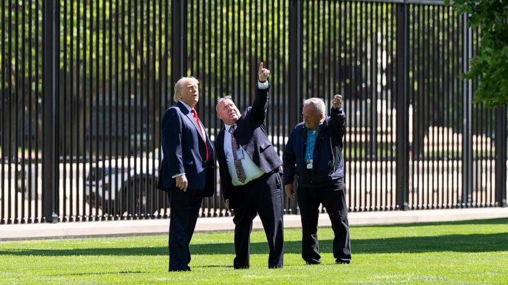 PHOTO: President Donald Trump speaks with Dale Haney, head White House grounds keeper, right, and others, about a new flagpole on the North Lawn of the White House, April 23, 2025, in Washington.