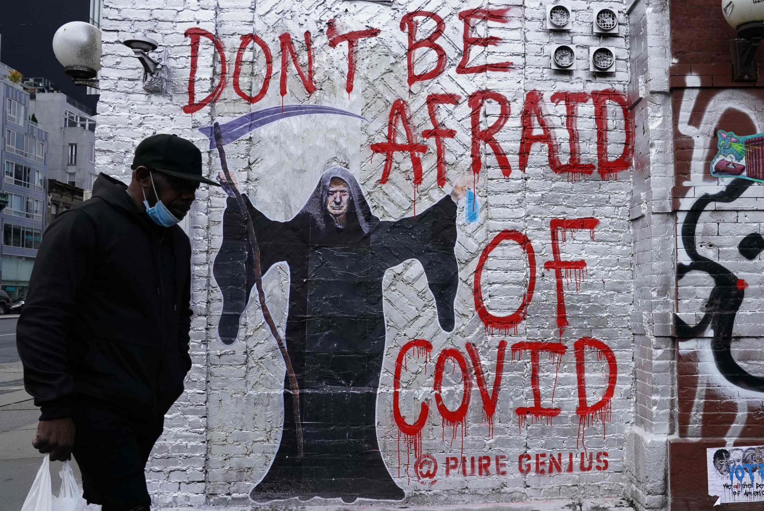 PHOTO: A man walks past a mural by the artist who goes by the name "Pure Genius" depicting U.S. President Donald Trump as the Grim Reaper on a wall on Houston Street in New York City on Oct. 20, 2020.