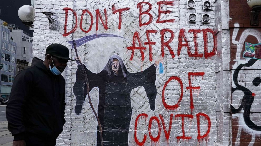 PHOTO: A man walks past a mural by the artist who goes by the name "Pure Genius" depicting U.S. President Donald Trump as the Grim Reaper on a wall on Houston Street in New York City on Oct. 20, 2020.