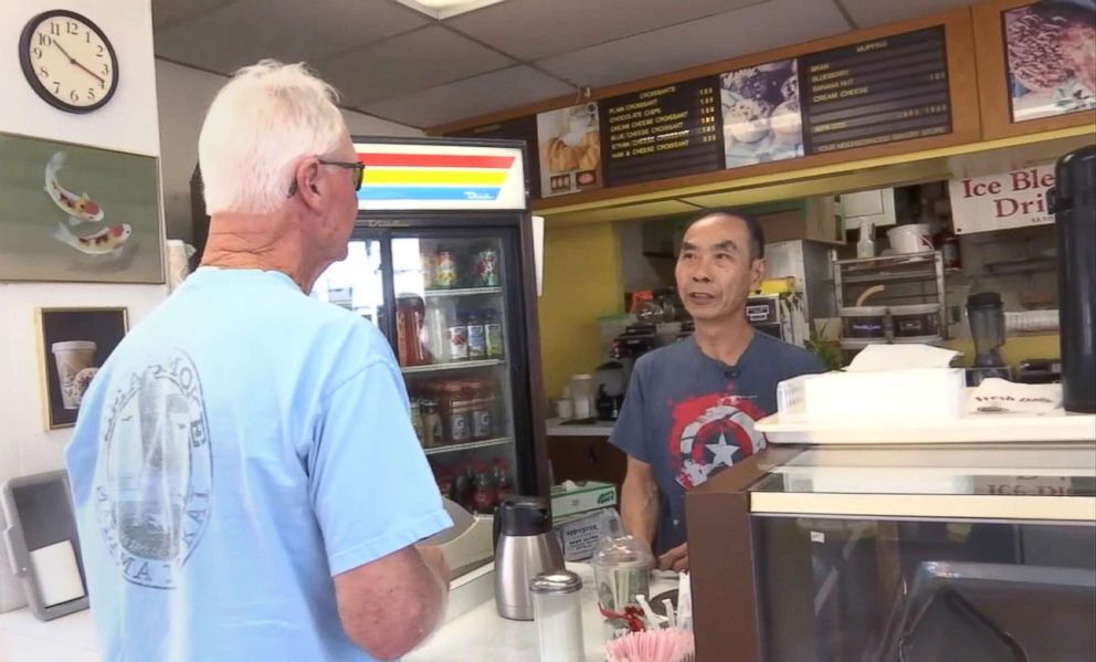 PHOTO: Donut shop owner John Chhan helps one of his customers in Seal Beach, Calif. When his wife, Stalla, fell ill, customers bought up his daily supply so he could close shop and head home to take care of her.