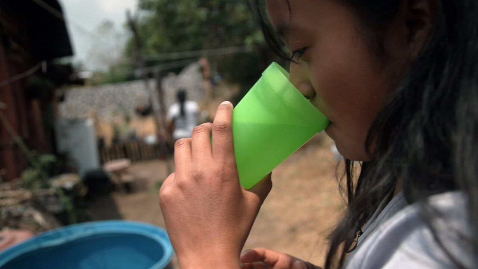 woman drinking water from plastic cup, isolated on a white