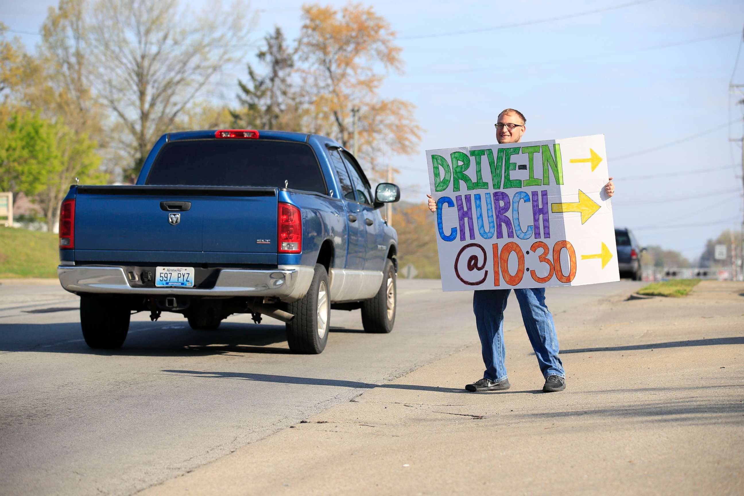 PHOTO: A worshiper holds a sign to alert drivers to the drive-in service at On Fire Christian Church on April 5, 2020 in Louisville, Kentucky. Due to COVID-19 limiting gatherings of people, churches have responded with alternate services. 