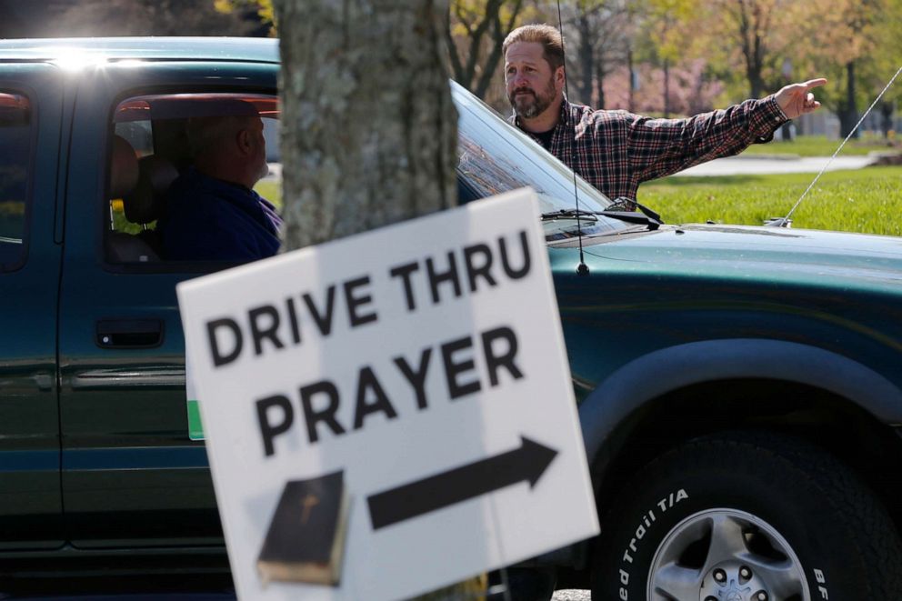 PHOTO: George DeCola, of Richmond, talks with someone who drove up for a prayer at a shopping center Thursday April 2, 2020, in Richmond, Va. DeCola, who is a worship leader at a Lutheran Church offers prayers for those wanting spiritual guidance.