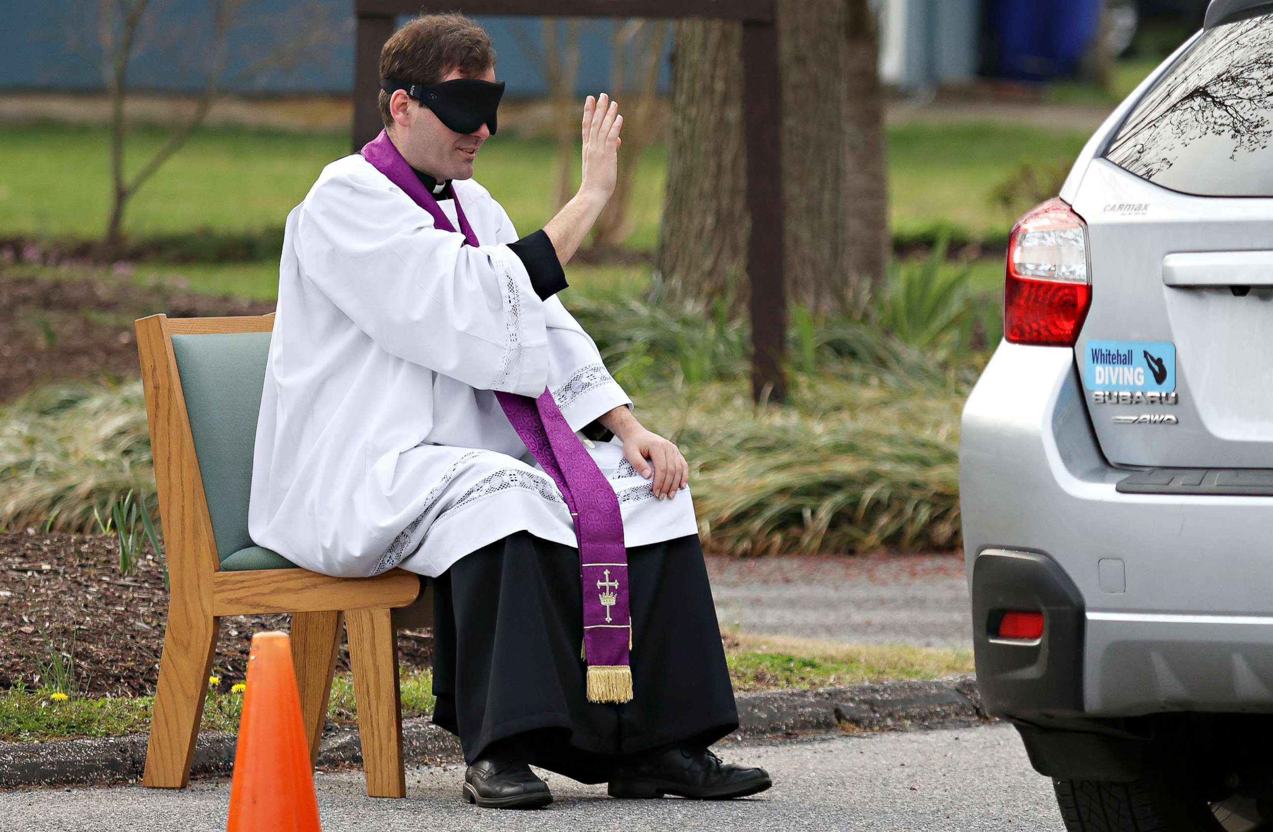 PHOTO: Father Scott Holmer, of St. Edward the Confessor Catholic Church, makes the sign of the cross while holding confession in the church parking lot, on March 20, 2020, in Bowie, Md.