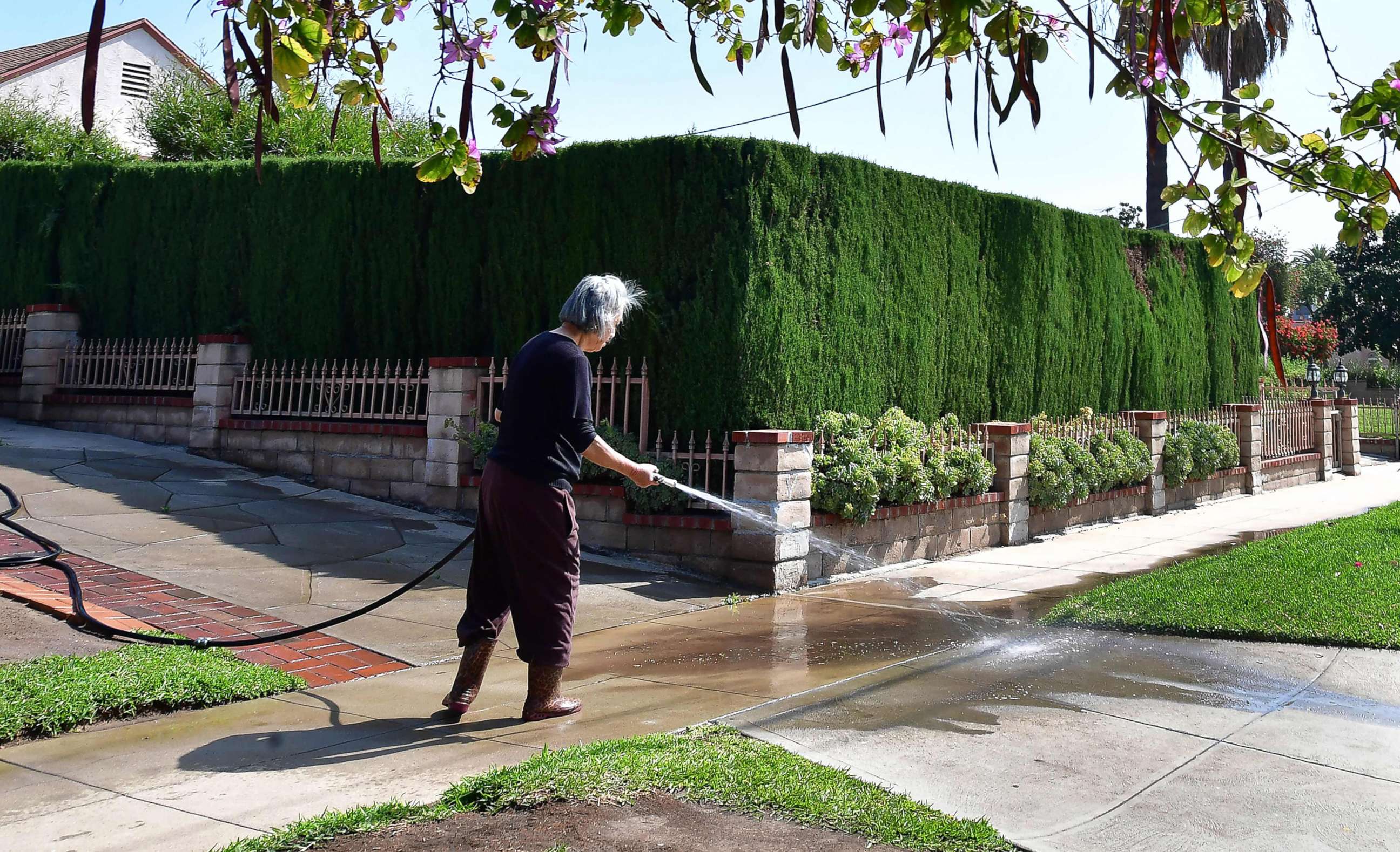 PHOTO: A woman waters down her driveway in Monterey Park, Calif., April 27, 2022, a day after Southern California declared a water shortage emergency.