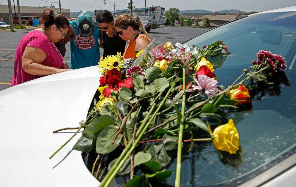People pray next to a car believed to belong to a victim of a last night's duck boat accident, Friday, July 20, 2018 in Branson, Mo. The tourist town mourned Friday for more than a dozen sightseers who were killed when a duck boat capsized and sank.