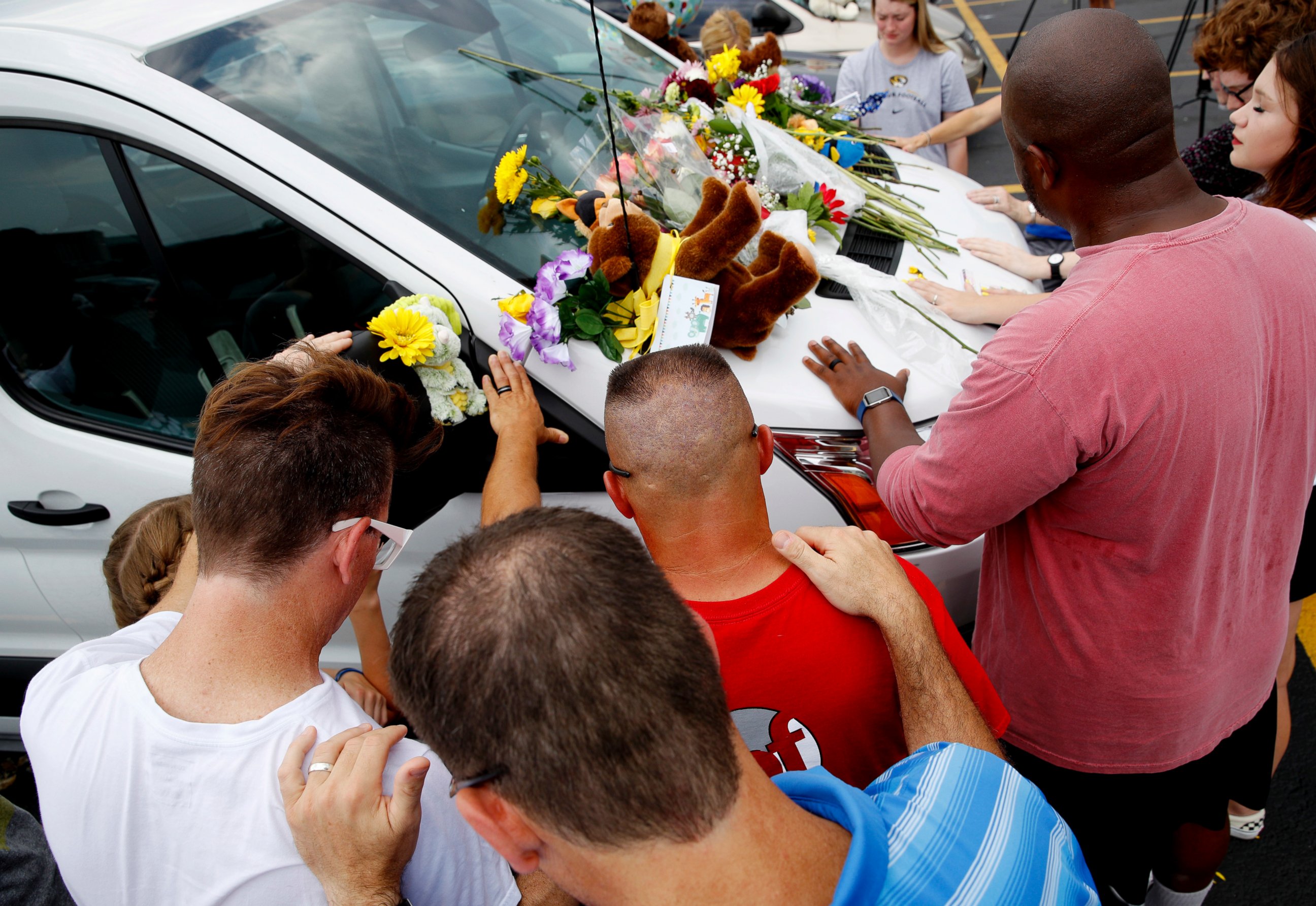 People pray around a van believed to belong to victims of a duck boat accident in the parking lot of the business running the boat tours Friday, July 20, 2018 in Branson, Mo.