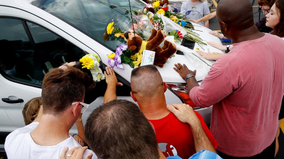 People pray around a van believed to belong to victims of a duck boat accident in the parking lot of the business running the boat tours Friday, July 20, 2018 in Branson, Mo.