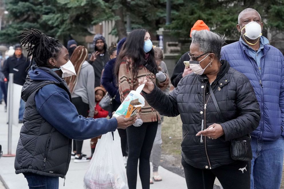PHOTO: A worker hands out disinfectant wipes and pens as voters line up to enter a polling site for Wisconsin's primary election in Milwaukee, April 7, 2020.