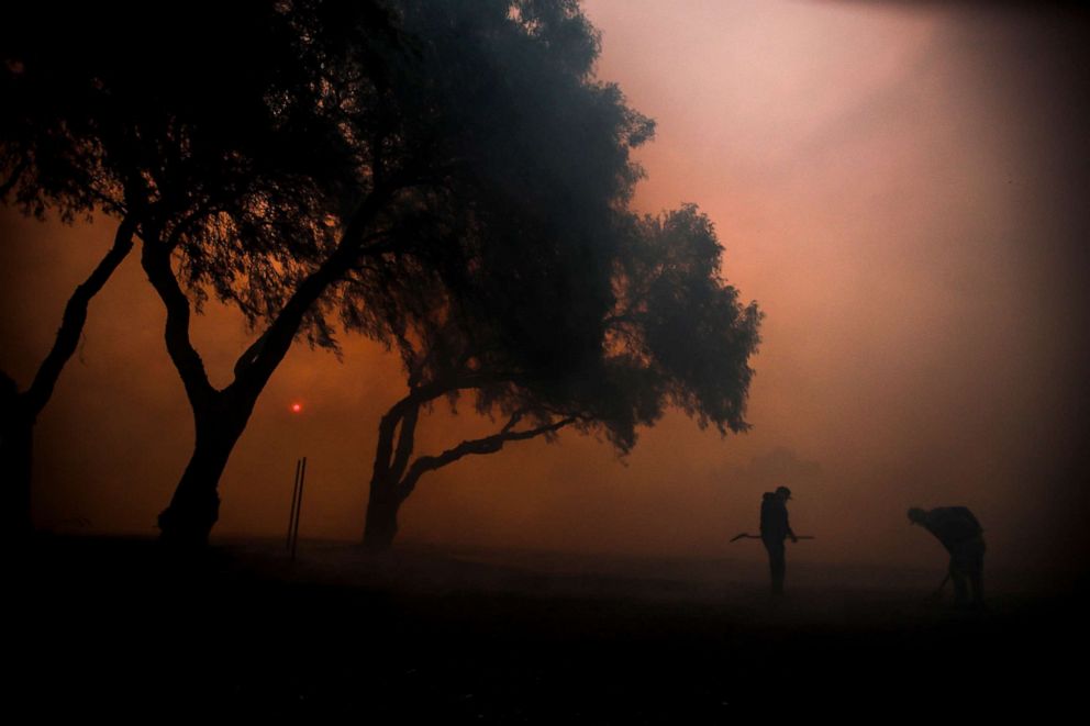 Workers shovel ambers and dispose of them in a ranch as the Easy Fire spreads in Simi Valley, North of Los Angeles, Oct. 30, 2019.