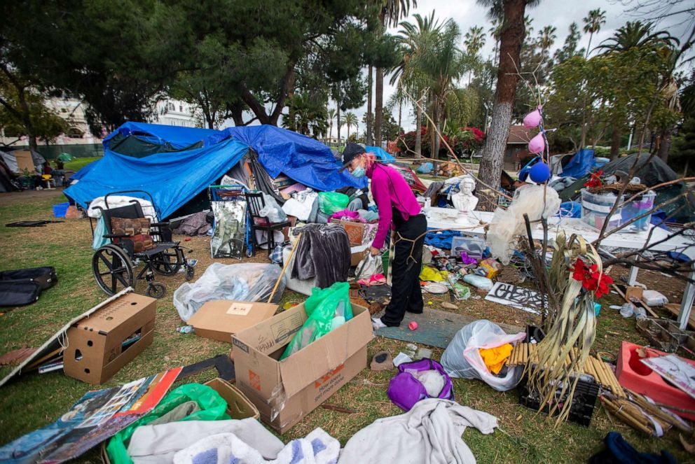 PHOTO: Valerie Zeller trying to organize her belongings as she is packing outside her tent next other tents at Echo Park Lake, March 25, 2021, in Los Angeles.