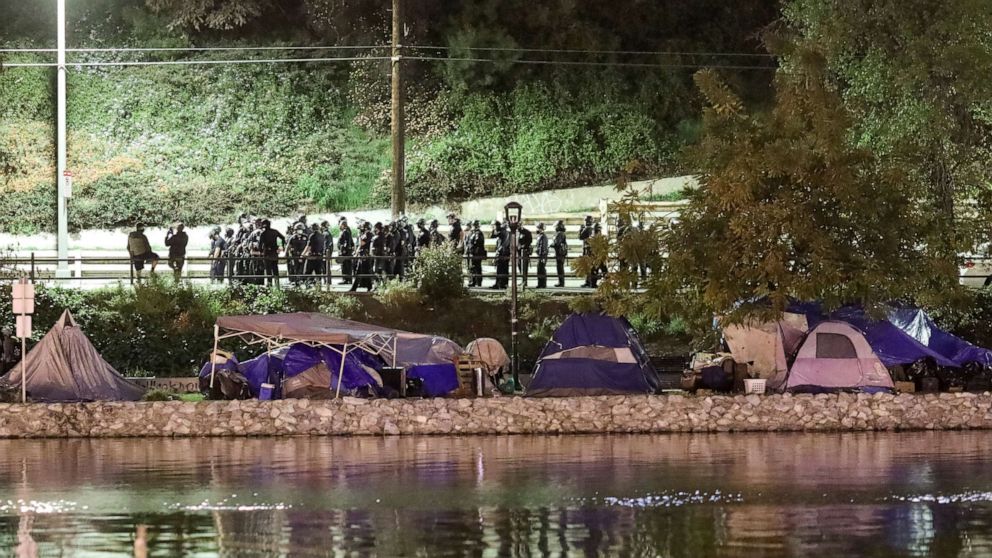 PHOTO: Police officers stand near the Echo Park Lake, as they prepare for the eviction of the homeless encampments, amid the outbreak of COVID-19, in Los Angeles, March 25, 2021.